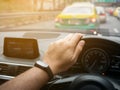 hand of man holding and controls steering wheel of his car, traveling in the city on the traffic jam road Royalty Free Stock Photo