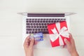 Hand of man holding credit card and online shopping for giving gift box with laptop computer on wooden background. Royalty Free Stock Photo