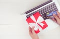 Hand of man holding credit card and online shopping for giving gift box with laptop computer on wooden background. Royalty Free Stock Photo