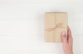 Hand of man holding gift giving on wooden table in Christmas day or holiday, present box for anniversary or birthday. Royalty Free Stock Photo