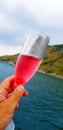 Hand of man holding glass of red wine with sea, mountain and sky background. Royalty Free Stock Photo