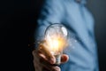 Hand man holding illuminated lightbulb, idea, innovation and inspiration with glowing virtual brain, smart intelligent creativity Royalty Free Stock Photo