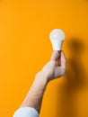 The hand of a man holding a light bulb for innovation and creative concept. Light bulb in hand on a yellow background. Empty space Royalty Free Stock Photo