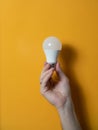 The hand of a man holding a light bulb for innovation and creative concept. Light bulb in hand on a yellow background. Empty space Royalty Free Stock Photo