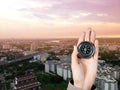 The hand of a man holding a magnetic compass over a city buildings
