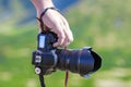 Hand of a man holding professional digital camera on blurred gre Royalty Free Stock Photo