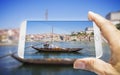 Hand of man holding a smartphone with a picture of a typical portuguese boats used in the past to transport the famous port wine