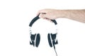 Hand holding stereo headphones against white wall