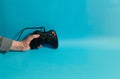 Hand of a man holding a video console controller on a blue background Royalty Free Stock Photo