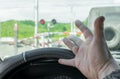 The hand of man inside the car. The car stopped in front of a closed barrier