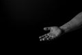 Hand of a man palm up reaching, on black background, giving a helping hand. Give me your hand concept.