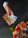 hand of a man paying with Costa Rican money for a bouquet of flowers