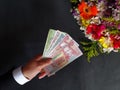 hand of a man paying with guatemalan money for a bouquet of flowers