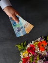 hand of a man paying with New Zealand money for a bouquet of flowers