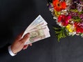 hand of a man paying with Russian money for a bouquet of flowers