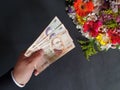 hand of a man paying with uruguayan money for a bouquet of flowers