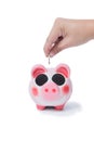 Hand of a man placing a coin into the slot of a piggy bank in a Royalty Free Stock Photo