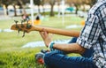 Hand of man playing guitar sitting on the grass Royalty Free Stock Photo