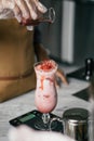 a Hand man pouring fresh milkshake into glass