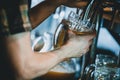 Hand of man pouring tankard of frothy draught beer from stainless steel beer tap in bar or pub into large glass tankard Royalty Free Stock Photo