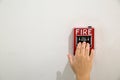 Hand of man pulling fire alarm switch on the white wall as background for emergency case at the new factory building. Royalty Free Stock Photo