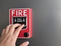 The hand of man pulling red fire alarm on gray background Royalty Free Stock Photo
