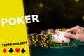 Hand of man raising aces from green table. Stacks of chips standing nearby, black background. Poker, texas holdem, card