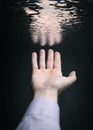 Hand of a man reflected in water surface.