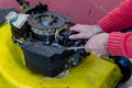 Hand of man repairing old grass cutter with tools on cement floor. Repairing lawn mower engine Royalty Free Stock Photo