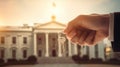 the hand of a man in a suit holds a key against the backdrop of the White House Royalty Free Stock Photo