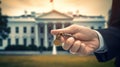 the hand of a man in a suit holds a key against the backdrop of the White House Royalty Free Stock Photo