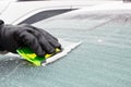 Hand of man using green scraper to remove ice from window in car, winter problems Royalty Free Stock Photo