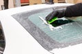 Hand of man using green scraper to remove ice from window in car, winter problems Royalty Free Stock Photo