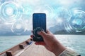 Hand of man using mobile smart phone against scenic landscape of boat view in the big river and reservoir dam with mountain and Royalty Free Stock Photo