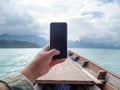 Hand of man using mobile smart phone against scenic landscape of boat view in the big river and reservoir dam with mountain and