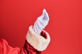 Hand of a man wearing santa claus costume and gloves over red background doing italian gesture with fingers together, Royalty Free Stock Photo