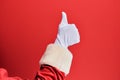 Hand of a man wearing santa claus costume and gloves over red background doing successful approval gesture with thumbs up, Royalty Free Stock Photo