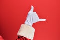 Hand of a man wearing santa claus costume and gloves over red background gesturing hawaiian shaka greeting gesture, telephone and Royalty Free Stock Photo