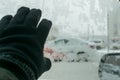 Human hand on the icy glass of the car with snow patterns