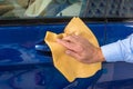 The hand of man wipes a car a yellow rag