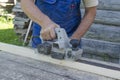 The hand of a man working with a planer and planer boards. Carpenter working with electric planer on wooden plank outdoor. Royalty Free Stock Photo