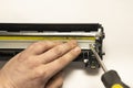 The hand of the master holds the disassembled part of the laser printer cartridge