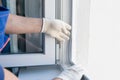 The hand of the master in a protective glove, inserts into the frame of the plastic window, an elastic band for sealing