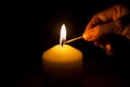 Hand with matchstick, lighting a candle