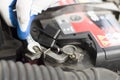 The hand of a mechanic with a flat key unscrews the battery in the car.
