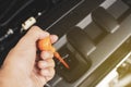 Hand of mechanic has pull yellow dipstick for checking engine oil level of a car. Royalty Free Stock Photo