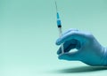 Hand in medical blue glove holding syringe. Blue background. Royalty Free Stock Photo