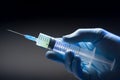 Hand in medical blue glove holding syringe. Grey background. Royalty Free Stock Photo