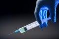 Hand in medical blue glove holding syringe. Grey background. Royalty Free Stock Photo