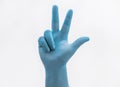 Hand with medical blue latex protective gloves showing three fingers on white background Royalty Free Stock Photo